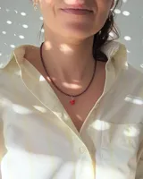 Gargantilla de cuentas facetadas color borgoña con cierre de mosquetón dorado y cadena de alargue. Incluye cuatro dijes colgantes dorados: cerezas con strass rosa, frutilla roja, corazón rojo esmaltado y estrella con strass.