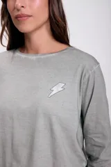 Remera gris de manga larga con estampado de rayo en el pecho.