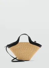 Bolso tipo tote de paja color beige con detalles en cuero sintético negro. Tiene doble asa de mano y correa larga al hombro.