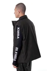 Chaleco negro con estampado de logos, cierre desmontable, broches snap ocultos, bolsillos frontales, elástico con tanca en la cintura e interior de tafeta relleno de guata.