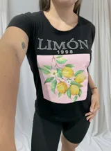 Remera negra de algodón con cuello redondo y mangas cortas. Estampado frontal con la palabra "Limón" y un diseño de limones con hojas y flores sobre un fondo rosa.