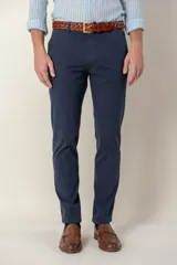 Pantalón de vestir azul marino, de corte slim fit, con bolsillos laterales y traseros. Se ajusta a la cintura con cinturón de cuero marrón.