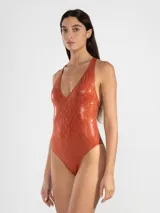 Malla entera color ladrillo con estampado de piel de serpiente, escote en V y espalda descubierta con tiras cruzadas unidas por un detalle metálico cuadrado.