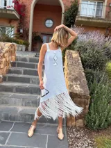 Vestido corto tejido en lurex con diseño geométrico en cuero en el frente, breteles de cuero intervenido a mano con tientos de cuero plateado y terminación en flecos.