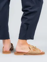 Sandalias bajas color beige con diseño tejido y detalle de hebilla dorada.