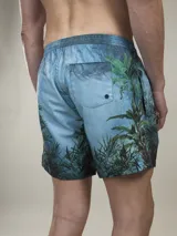 Short de baño verde con estampado de margaritas blancas y cordón ajustable naranja.