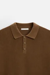 Polo marrón de punto con hilatura de algodón, corte relaxed fit, cuello solapa con cierre frontal de botonadura, manga larga y acabados en rib.