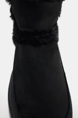 Botín negro con interior de efecto pelo, suela tipo flatforma y acabado en punta redonda.