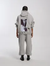 Buzo hoodie oversize de felpa de algodón color gris, con capucha y bufanda integrada que envuelve el cuello. Presenta cierre frontal y bolsillos canguro.