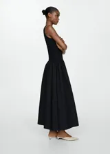 Vestido largo de punto negro, sin mangas, con cuello redondo y corte evasé.