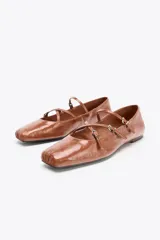 Zapato tipo bailarina color marrón de piel con acabado charol. Tiene punta cuadrada, detalle de tiras con hebillas metálicas y suela plana.