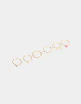 Set de seis anillos dorados de metal con diferentes diseños: texturado, con corazón, strass, mariposa y flor.