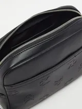 Neceser negro de cuero sintético con monograma CK grabado en relieve, cierre de cremallera, bolsillo exterior y asa de mano desmontable.