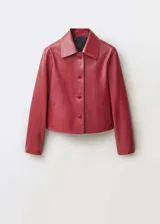 Chaqueta de cuero ovino color borgoña, de corte recto, con cuello camisero blanco, cierre frontal con botones y dos bolsillos de parche con solapa.