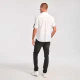 Camisa de popelina verde con cuello abotonado, cierre frontal con botones, bolsillo de parche en el pecho izquierdo, mangas largas con trabillas para enrollar y dobladillo camisero.