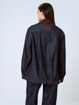 Chaqueta de denim azul oscuro con cuello de piel sintética color borgoña, cierre frontal con botones a presión, bolsillos de parche con solapa en el pecho y bolsillos laterales.