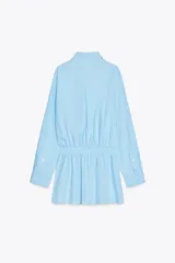 Vestido corto camisero celeste de algodón, con cuello solapa, manga larga con puños plisados, detalle de tablas en la falda y cierre frontal con botones.