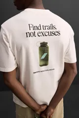 Camiseta color crudo de corte relaxed fit, cuello redondo y manga corta. Estampado con la frase "Find trails, not excuses" en el frente.
