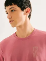 Camiseta blanca de algodón con cuello redondo y mangas cortas. Estampa rectangular con borde negro que contiene la frase "NATURAL ATMOSPHERE" en letras mayúsculas y una imagen de montañas y mar.