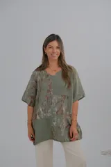 Blusa verde militar con estampado de hojas en tonos marrones y blancos, cuello en V y mangas cortas.