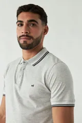 Chomba azul marino de manga corta con cuello polo y detalles de líneas grises en cuello y mangas. Tiene logo bordado en el pecho. Corte regular.