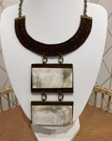 Collar con cadena de eslabones color bronce, con colgante de gamuza marrón en forma de medialuna y dos colgantes rectangulares de guampa con borde de gamuza marrón.