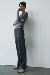 Pantalón de vestir gris oscuro de tiro bajo, con trabillas en la cintura, bolsillos delanteros y traseros, raya planchada y pierna recta.