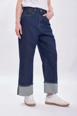 Pantalón de jean azul oscuro con bajo doblado.