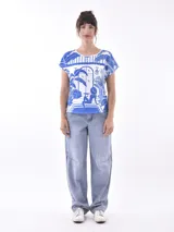 Remera blanca con estampado de paisaje en tonos azules.