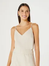 Musculosa color beige claro con escote en V y tirantes finos. El tejido parece ser una mezcla de lino o similar, con textura visible.