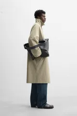 Gabardina color beige de corte amplio, con cuello solapa, manga larga, bolsillos laterales con solapa y cierre frontal con botones.