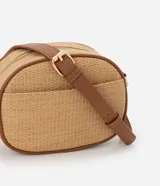 Cartera bandolera pequeña color beige con textura de paja y detalles en marrón. Tiene cierre de cremallera, bolsillo externo y asa larga regulable con hebilla.
