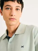 Camisa polo color rosa claro con cuello clásico, tapeta de dos botones y bordado de logo en el pecho. Presenta ribete azul marino en cuello y mangas. Corte clásico.