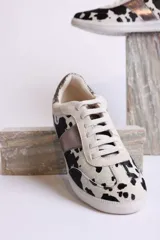 Zapatillas deportivas bajas con estampado animal print de vaca en blanco y marrón.