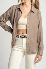 Camisa color marrón claro de gamuza vegana con calce oversize, cuello clásico, cierre frontal con botones y mangas largas con puños abotonados.