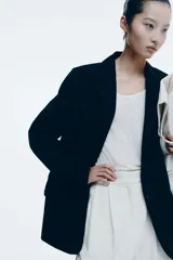 Blazer negro de sarga con solapas de muesca, hombreras, bolsillos ribeteados con solapa y forro interno.