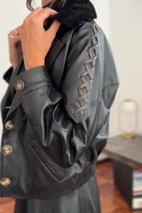 Campera bomber negra de cuero con cuello de piel sintética negra, forro interior y detalles de pasamanería en cuero marrón gastado en las mangas.