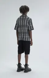 Camisa de manga corta tejida de punto abierto (símil crochet), calce oversize, color negro con diseño abstracto en beige.