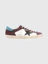 Zapatillas Golden Goose modelo Super Star, de cuero color marrón y blanco, con estrella negra en el lateral y detalles en celeste.