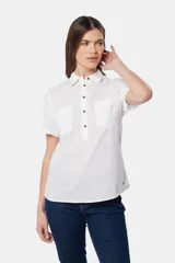 Camisa de lino color beige, de manga corta, con medio botón, dos bolsillos en el pecho y botones metálicos personalizados.