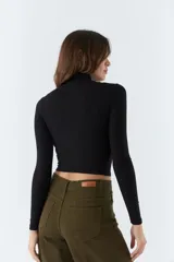 Polera color beige de corte crop, cuello alto y mangas largas.