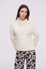 Polera color crudo con cuello alto y ajuste al cuerpo, de manga larga y textura suave.