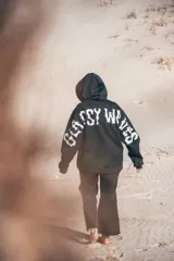 Buzo hoodie negro con estampa en la espalda y mangas con letras blancas.