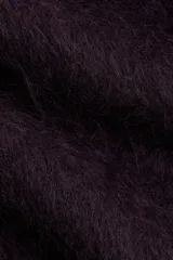 Buzo de punto oversized color morado oscuro, con textura suave y peluda, cuello redondo y hombros caídos.