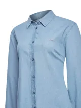 Camisa de denim celeste con cuello camisero, cierre frontal con botones y mangas largas.