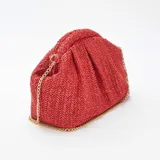 Bolso de mano tipo clutch, color rojo, confeccionado en rafia trenzada. Tiene forma rectangular con pliegues en la parte superior y cierre con broche imantado. Incluye una cadena dorada para usar como bandolera.