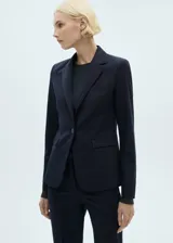 Blazer color beige con solapas de muesca, cierre frontal con un botón, hombros estructurados, corte entallado, forro interior y dos bolsillos de ribete en la parte delantera.