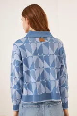 Cardigan azul con estampado de corazones geométricos en dos tonos de azul, con cuello polo y cierre frontal con botones.