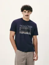 Camiseta blanca de algodón con cuello redondo y mangas cortas. Estampa rectangular con borde negro que contiene la frase "NATURAL ATMOSPHERE" en letras mayúsculas y una imagen de montañas y mar.