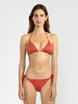 Conjunto de bikini rojo brillante con rayas verticales doradas. El corpiño es de triángulo con tirantes finos y la bombacha es de corte clásico con tiras ajustables a los costados.